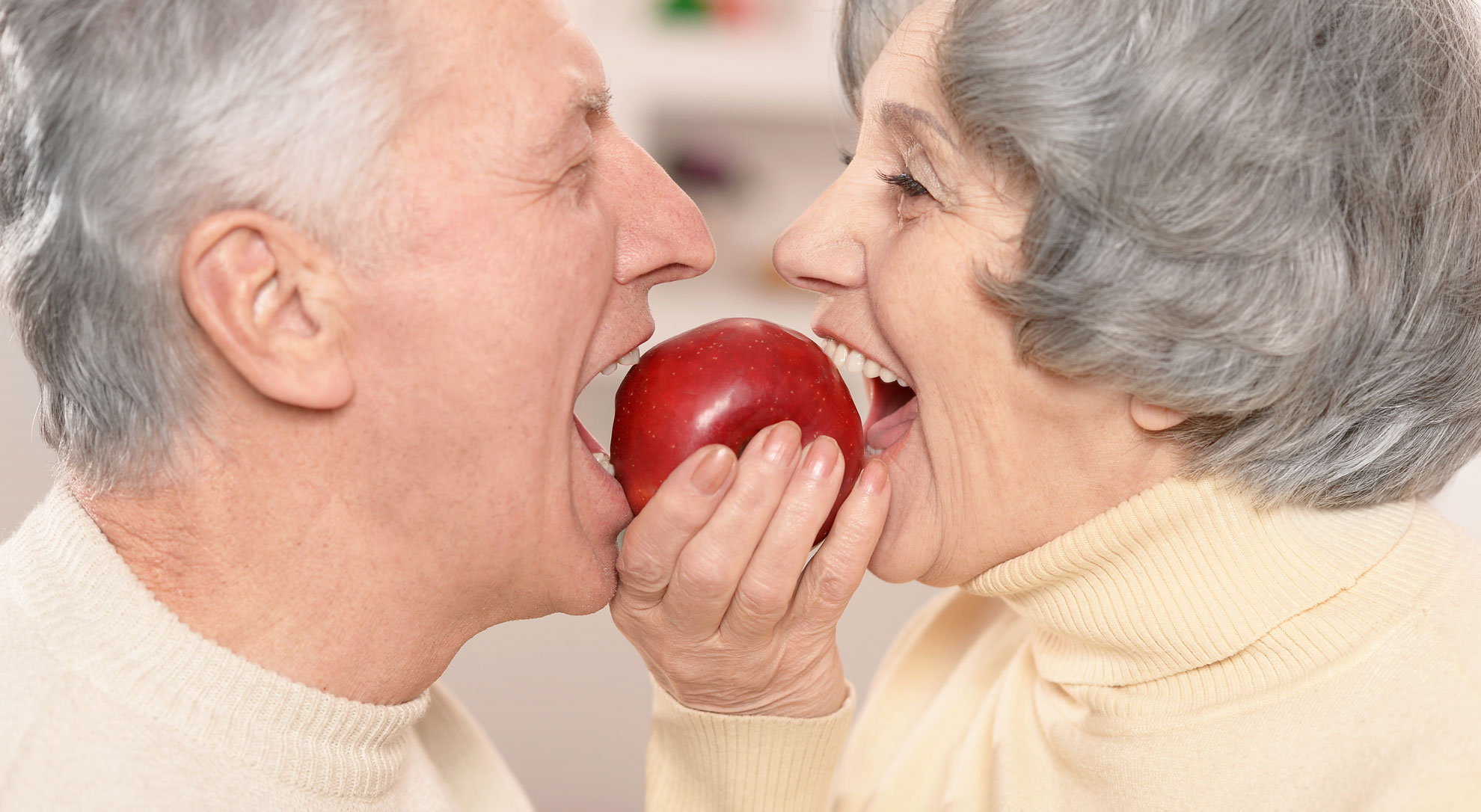 Пожилая женщина ест яблоко