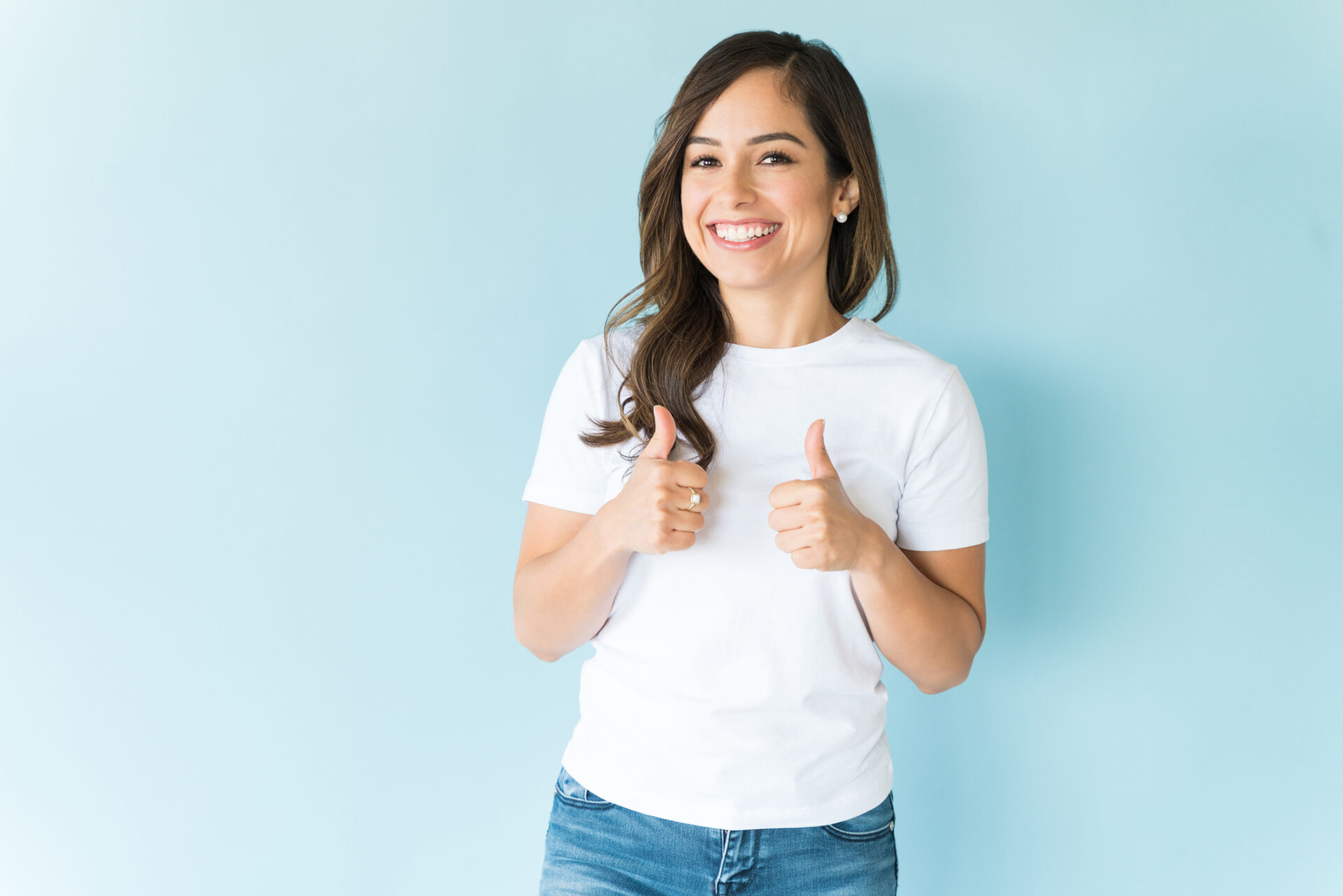 Woman Giving Thumbs Up Over Plain Background Dona somrient i assentint